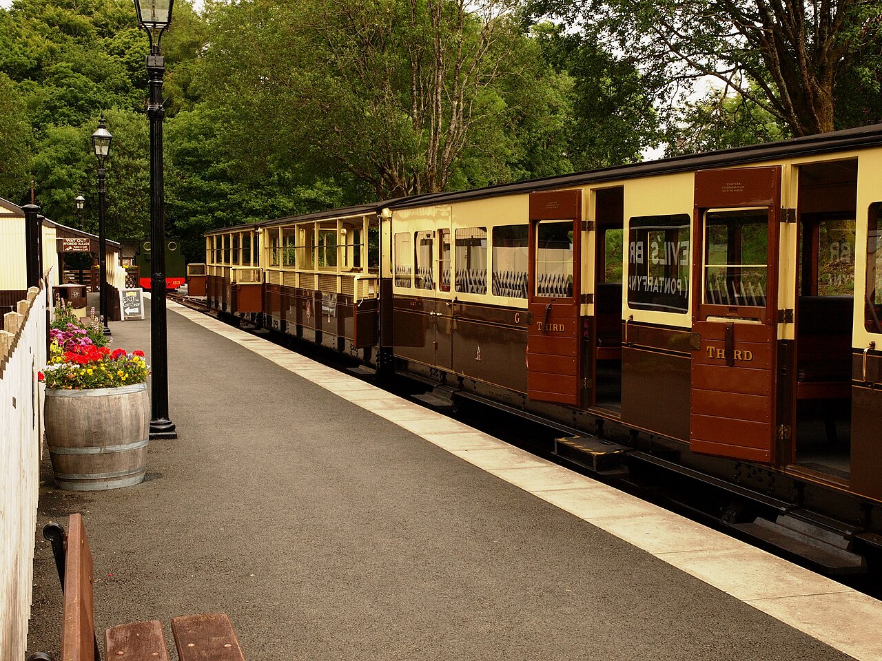 A vintage train standing at a station platform with open wooden doors, labeled Devil's Bridge
