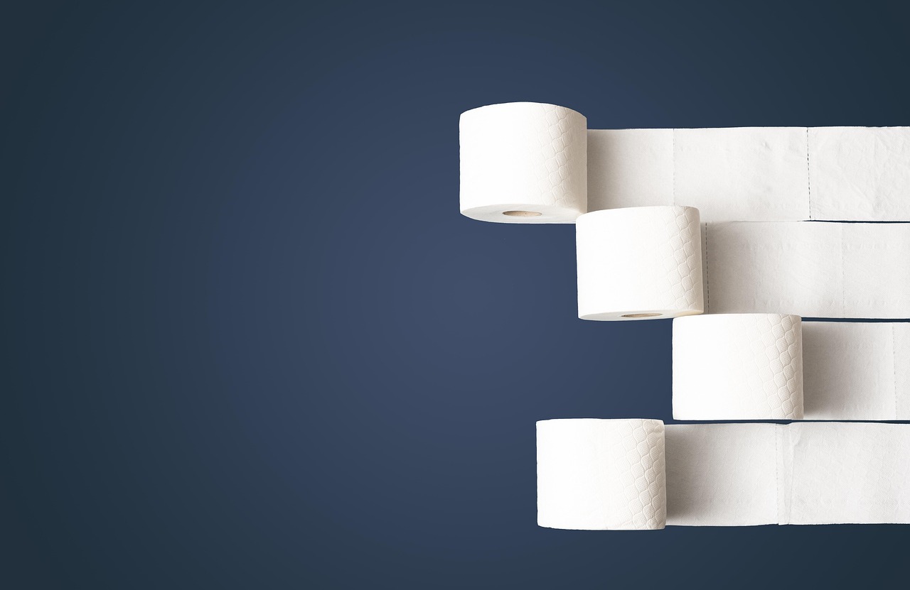 Four rolls of toilet paper with unrolled paper on a dark blue background.