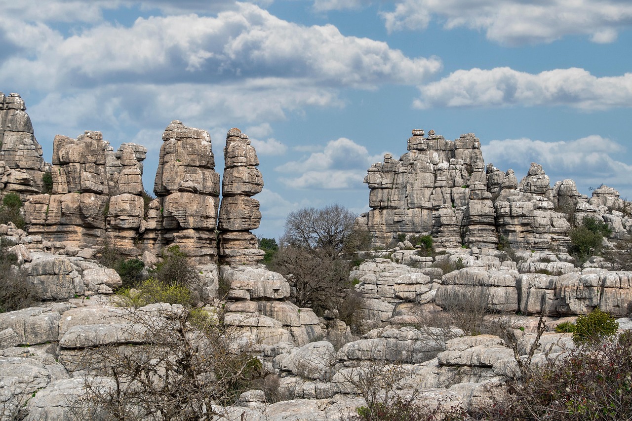 A landscape of ancient, weathered rock formations under a blue sky with clouds.