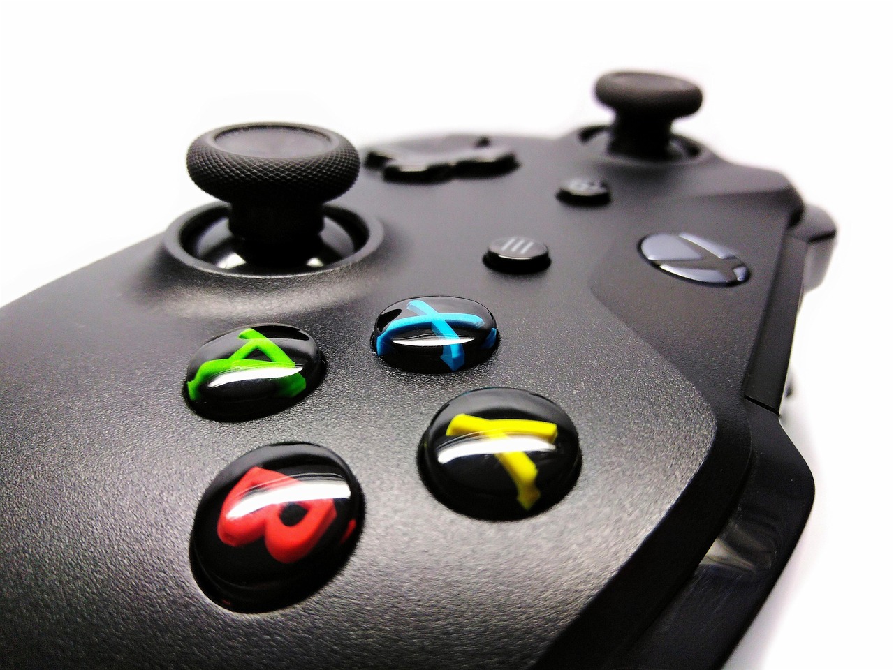 A close-up of a black video game controller with colorful buttons.