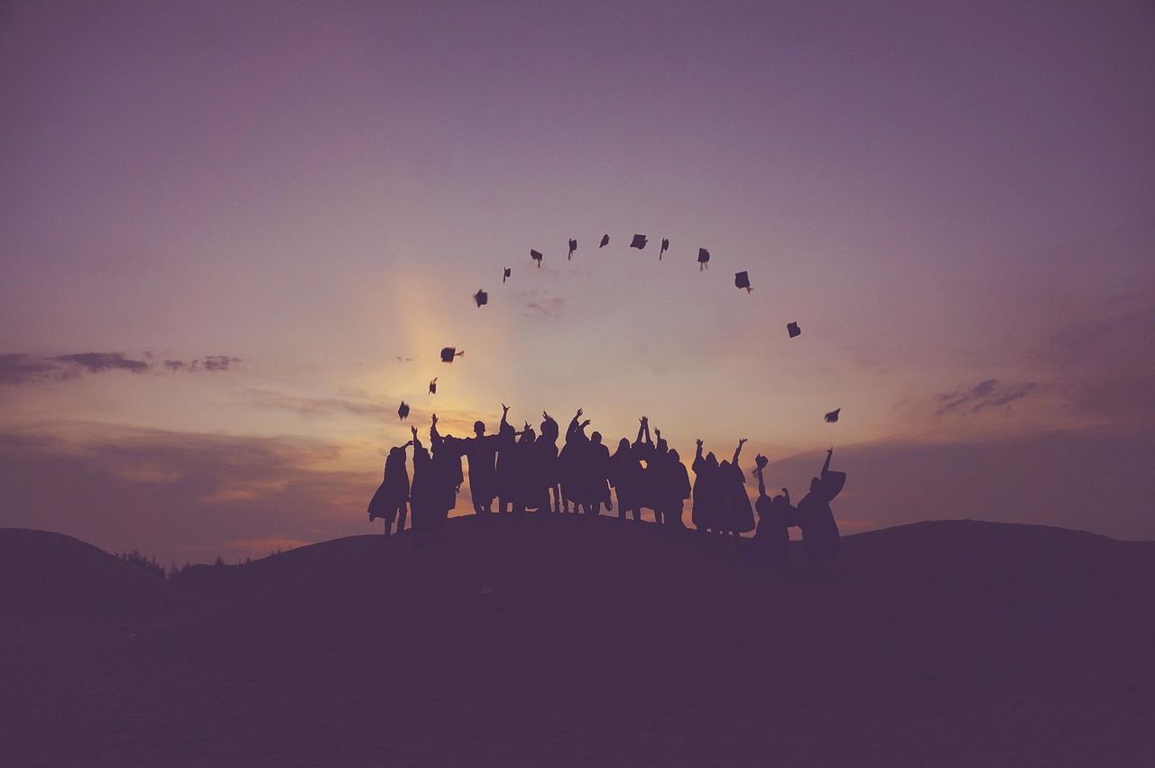 Silhouette of graduates throwing their caps in the air at sunset