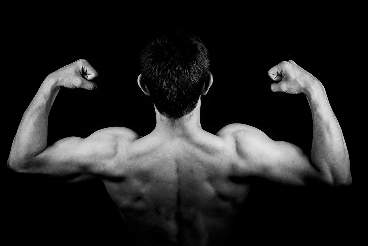 A black and white photo of a muscular person flexing their back muscles.