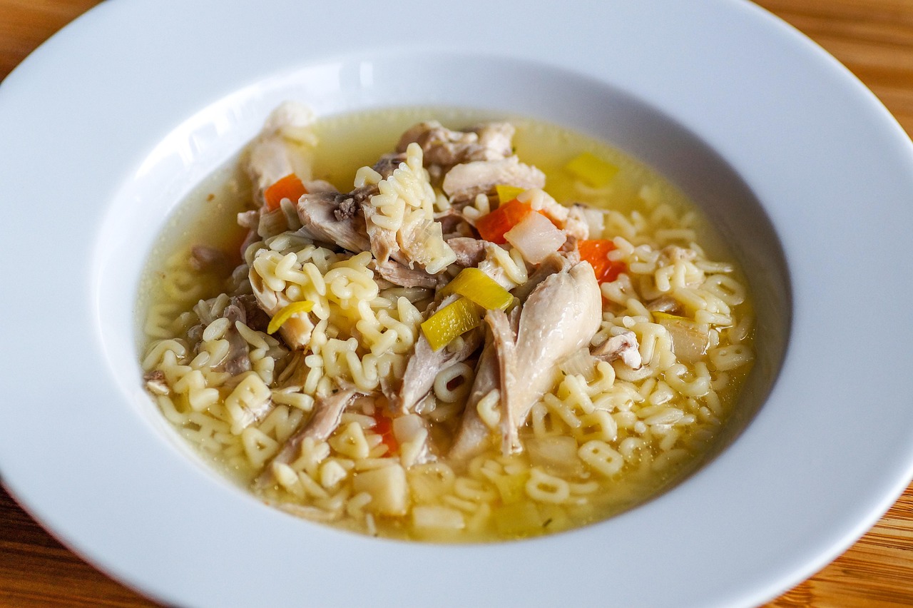 A bowl of chicken soup with alphabet-shaped pasta.