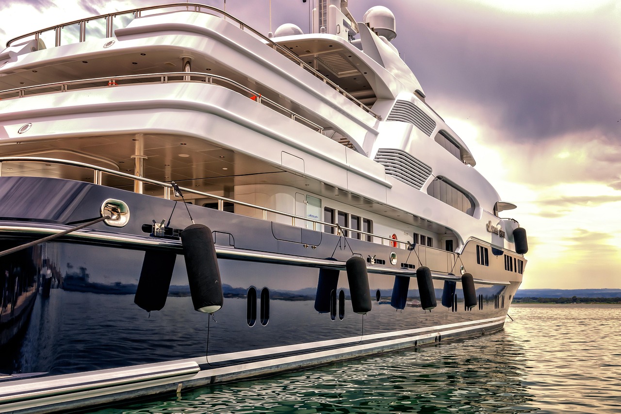 A large, modern luxury yacht docked on the water.