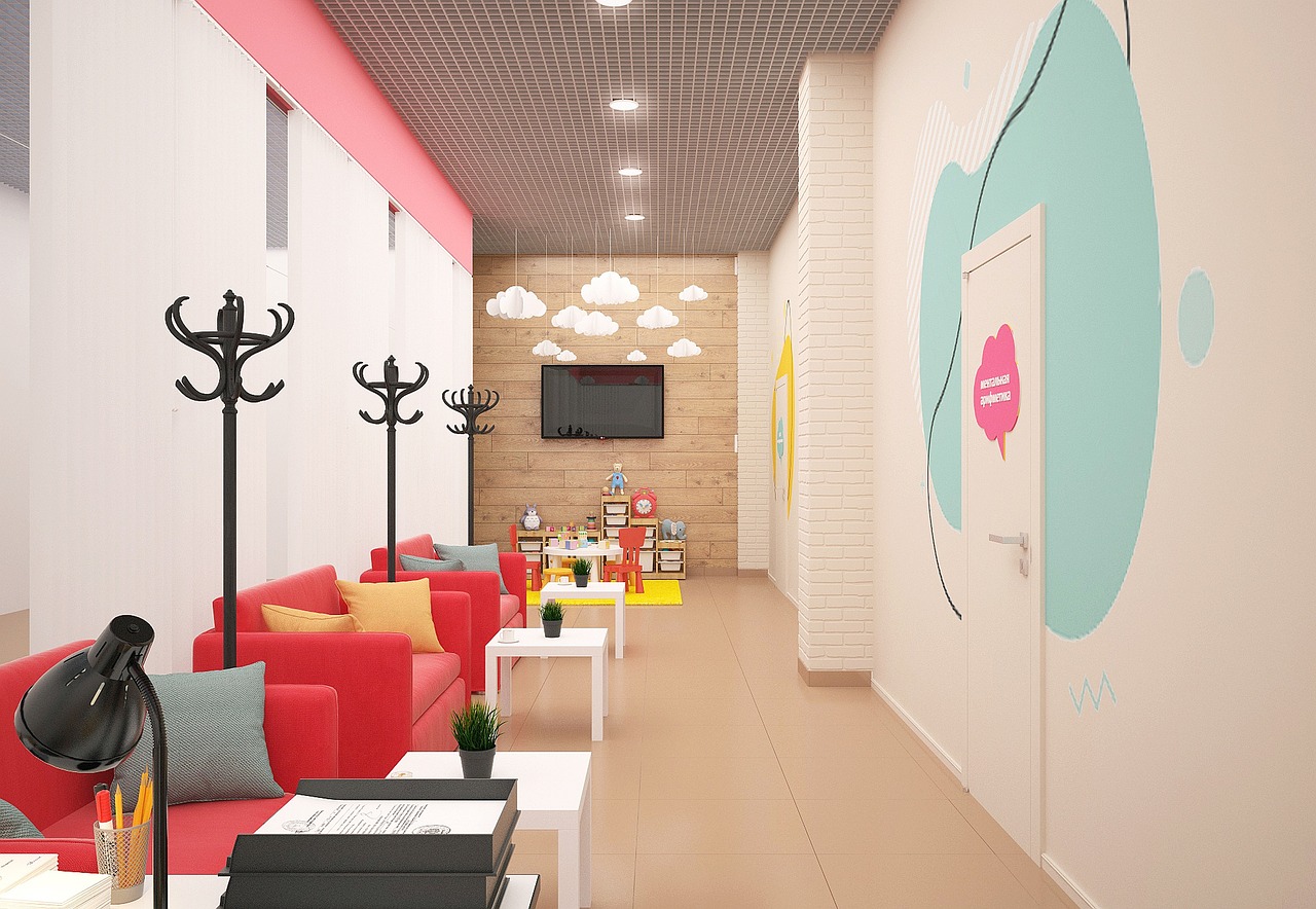 A bright, modern waiting room with red chairs and a small play area for children, suggesting a calm and welcoming environment.