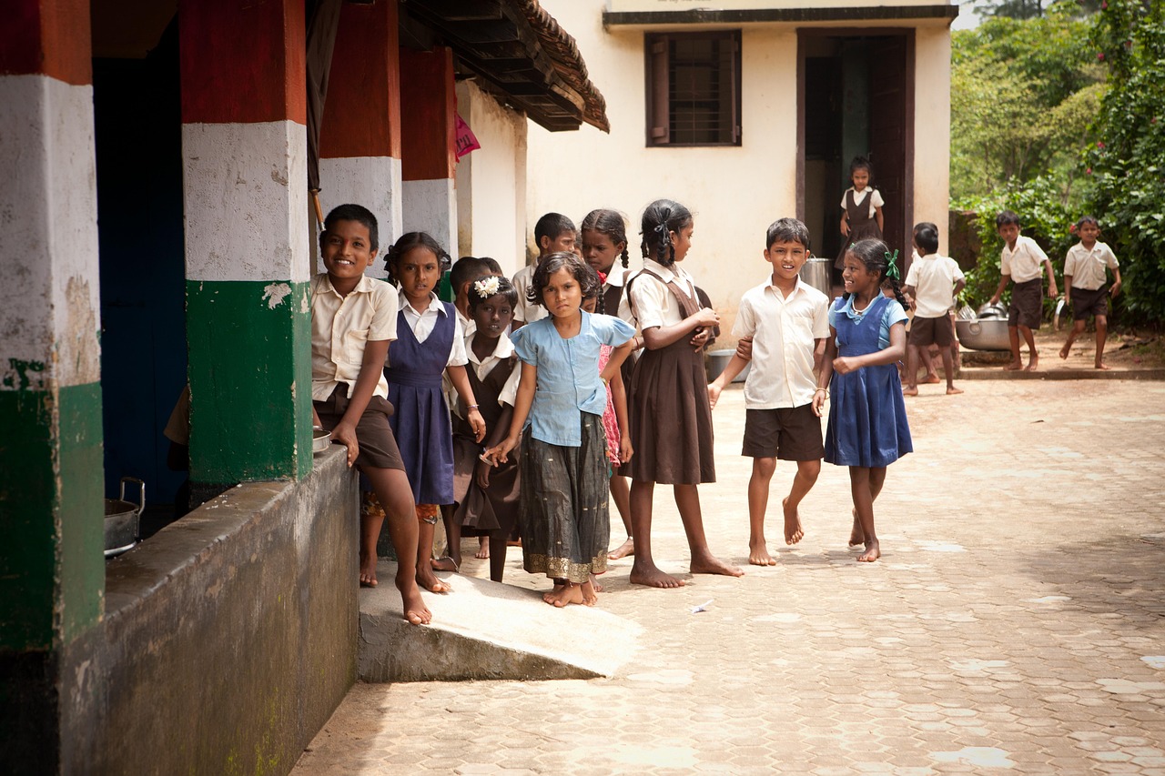 A group of school children in uniforms standing outside a school building in India.