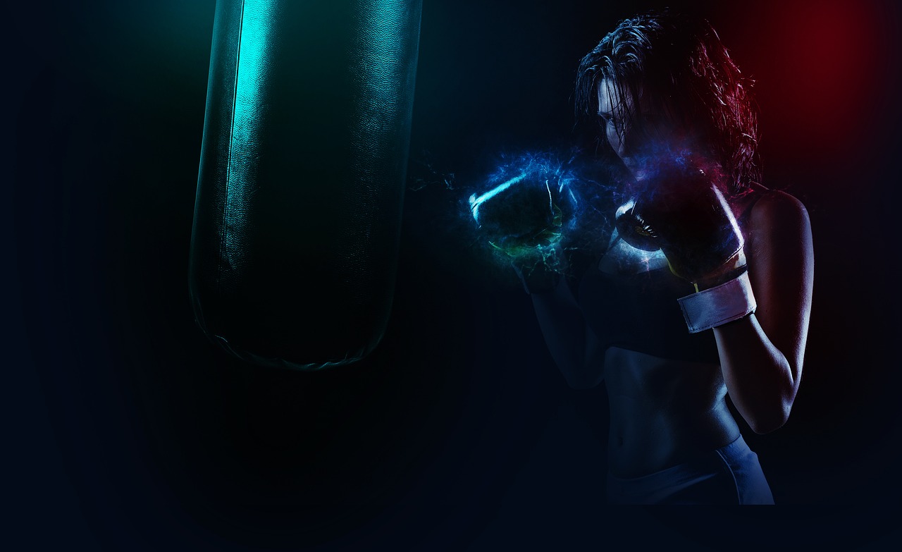 A person wearing boxing gloves training with a punching bag in a dark, moody setting.