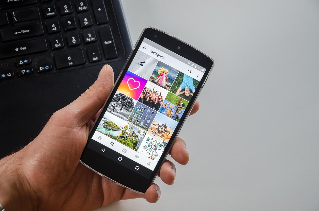 A person holding a smartphone displaying the Instagram app interface with a photo grid.