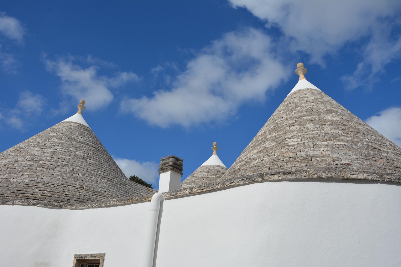 Close-up of the iconic conical stone roofs of a trullo house against a bright blue sky.