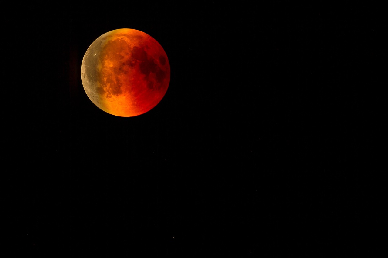 A bright, reddish-orange full moon against a dark night sky.
