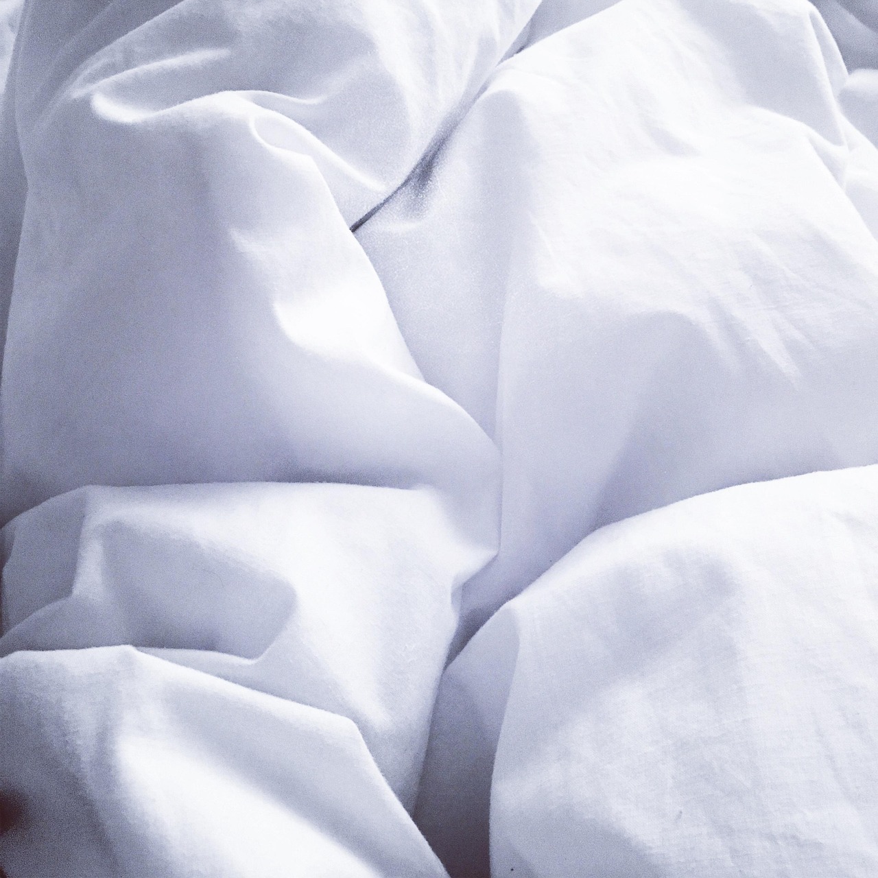 Close-up of white bed sheets with soft folds and texture