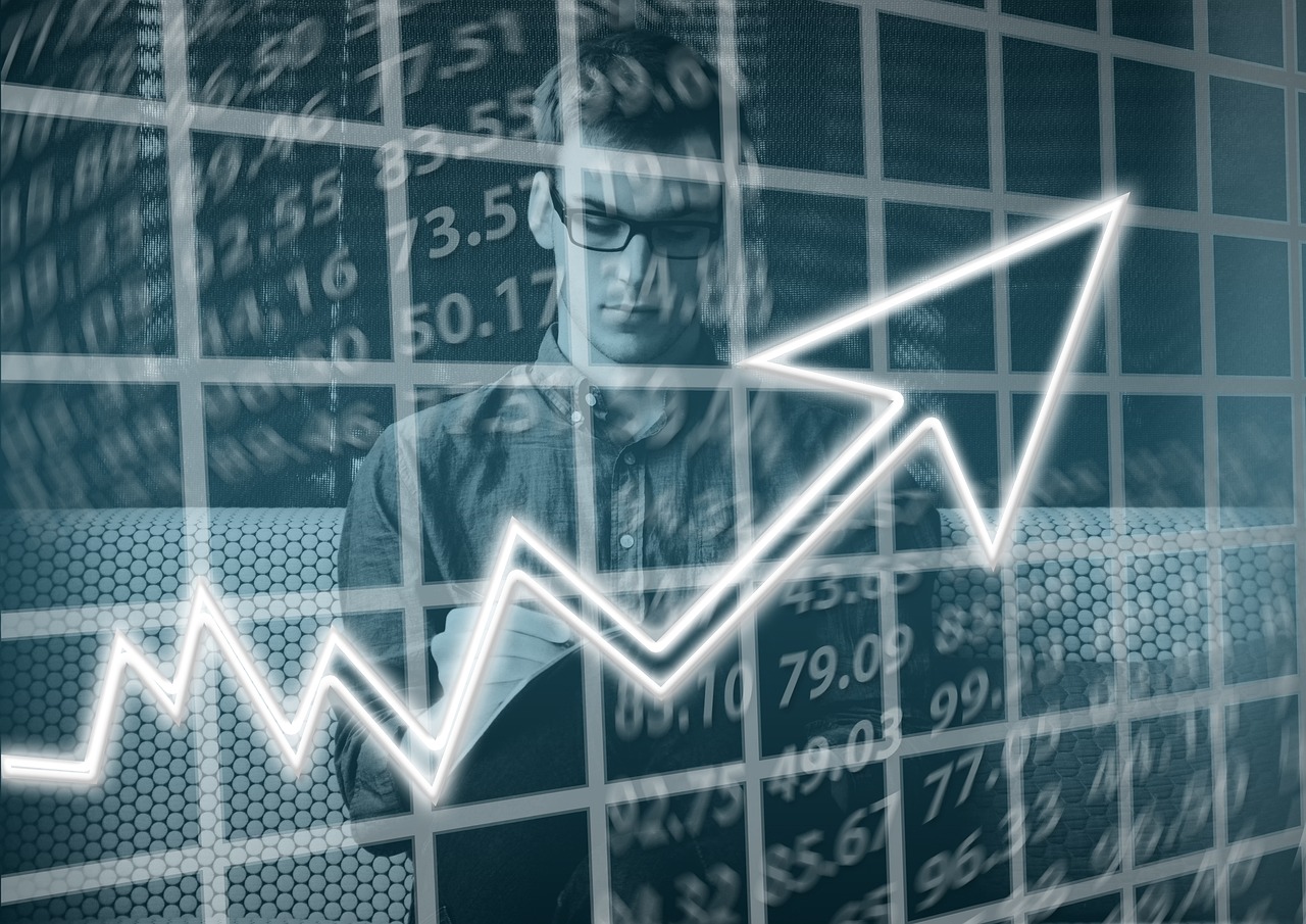 A man behind a financial chart with an upward pointing white arrow